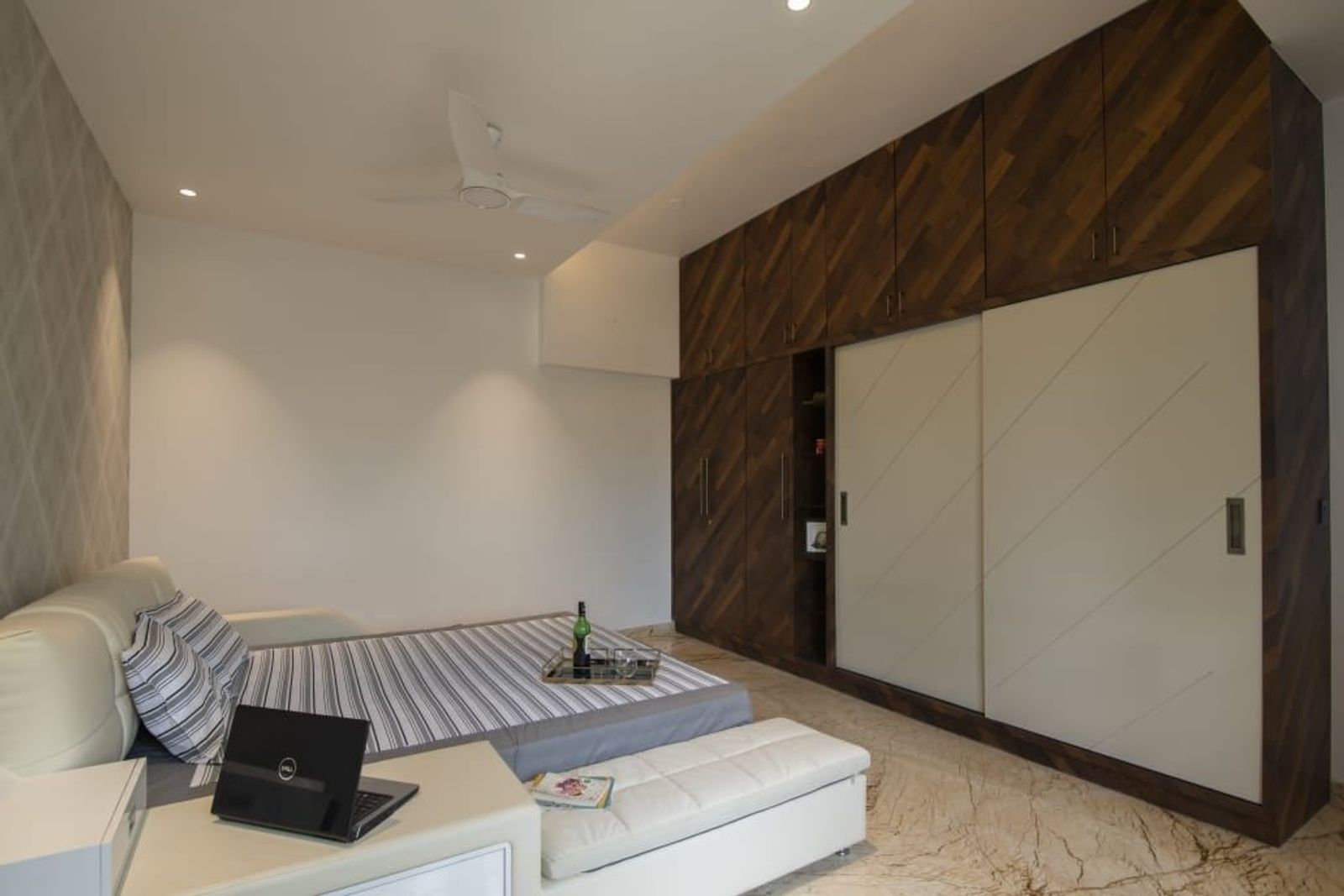 Sliding white wardrobe doors set into a wall of dark timber laid in a chevron
