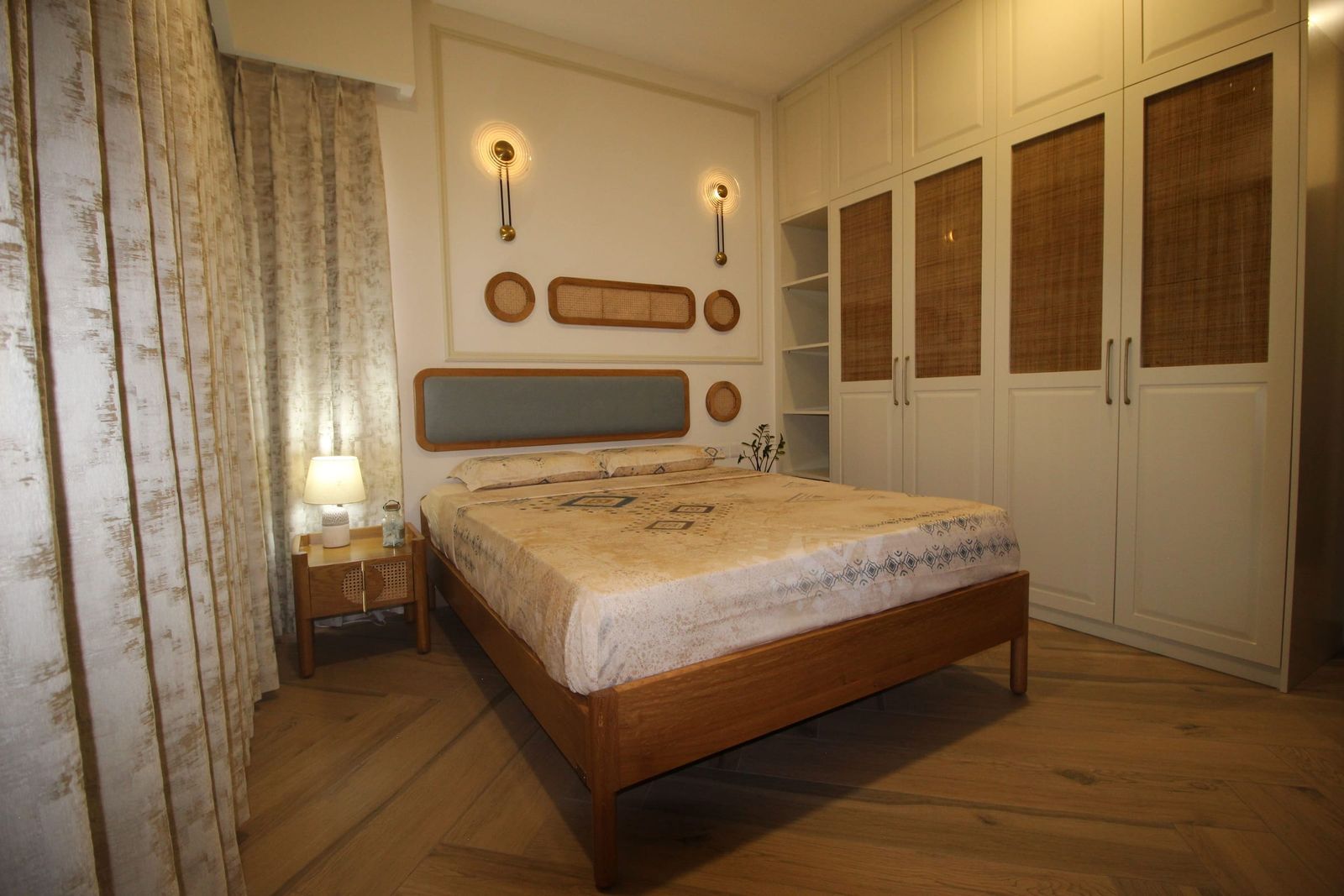 A bedroom with a full wall of cream wardrobes, rattan set into the doors