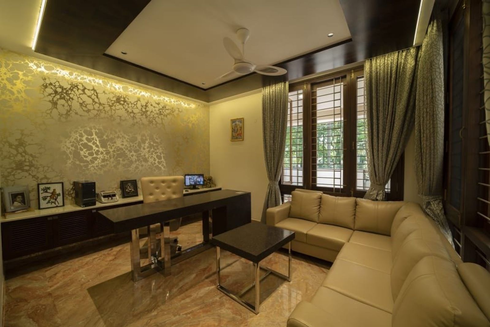 A study with a long desk under a lit ceiling, a sofa across the room